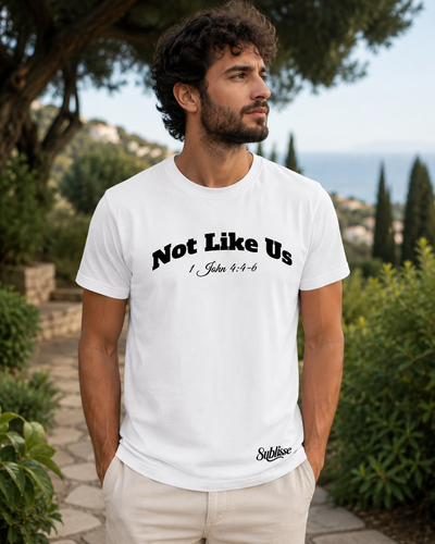 Not Like Us tee in white, worn in a garden